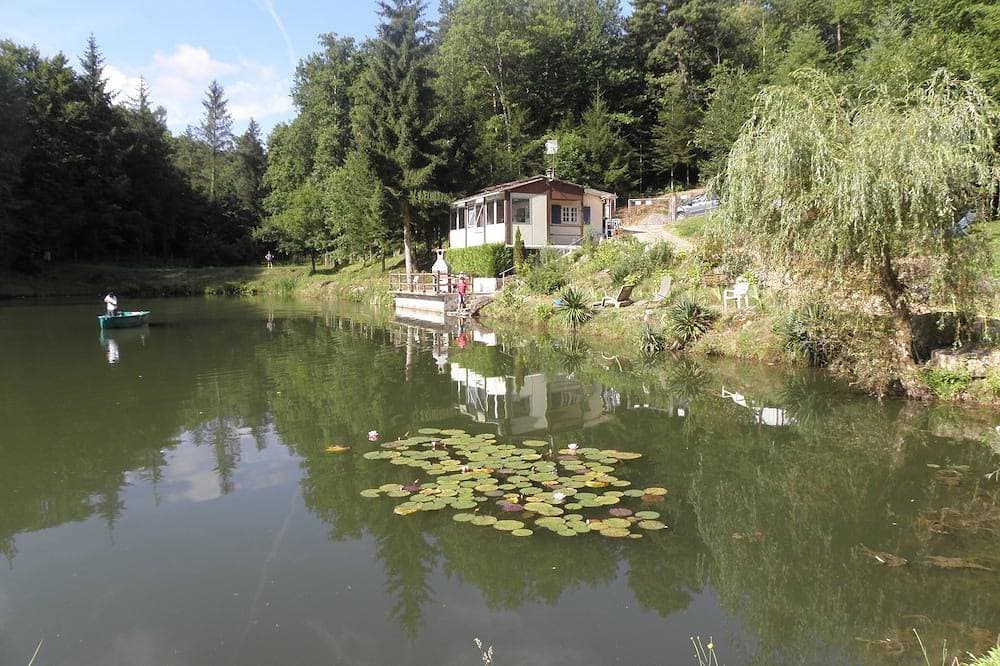 Chalet mit Blick auf einen Teich in einer grünen Umgebung. 1